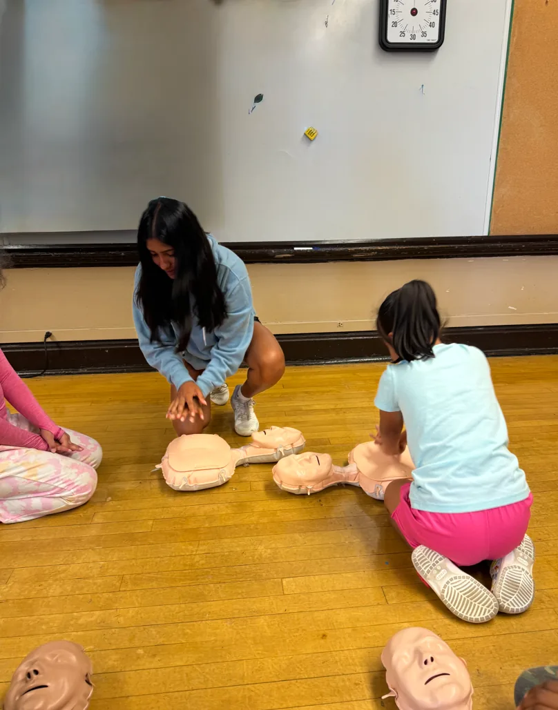 Leena Manadan teaching hands-only CPR to children at a Push to Save event